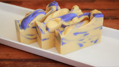 Swirled yellow and blue soap bar on a white plate with a wooden background